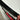 Carbon fiber spoiler edge with dark weave pattern and red reflection stripe