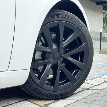 Dark multi-spoke wheel cover with center cap, fitted on a car wheel with tire