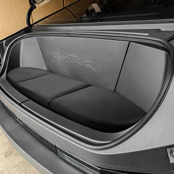 Front trunk seat cushion with dark padded seat, backrest panels, and faint emblem stitching.
