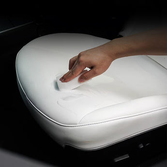 Leather seat cleaner wiping foam from a white leather car seat cushion