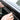 Carbon-fiber look side window rain guard visor trim, hands applying to car glass