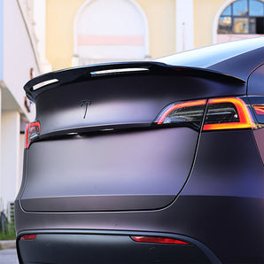 Glossy black trunk spoiler wing installed on rear deck of a car
