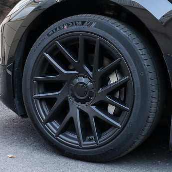 Close-up of 18-inch black multi-spoke wheel cover with center hub on tire