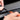 Hands press a black rubber seal into a car window channel using an orange tool.
