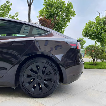 Matte black wheel cover with aero spoke design and circular center cap on rear wheel