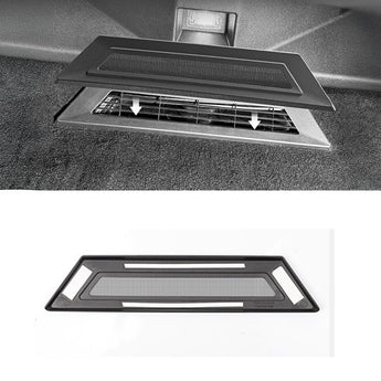 Under-seat vent cover installed, dark panel with mesh vent insert over floor opening.