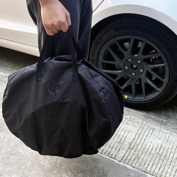 Wheel cover storage carrying bag, black, with handles, holding a wheel