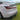 Side view of dynamic full-width LED taillight bar on white car with red glow