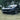 Glossy black front lip spoiler on the front bumper of a black sports car