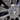 Wheel cover center cap close-up with angular spoke cutouts, dark satin finish