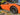 Dark aero wheel cover on front wheel of orange car, one-piece replacement