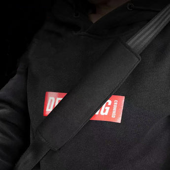 Black seat belt shoulder pad with visible red brand label on fabric