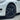 Wheel cover on a white car, dark multi-spoke design with center cap and visible tire tread