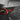 Dark carbon fiber charging port cover panel with cutout opening and red lens