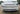 Front bumper grille insert installed on white car, dark mesh and slat design