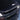 Close-up of carbon fiber rear wing spoiler edge on a dark vehicle, glossy weave