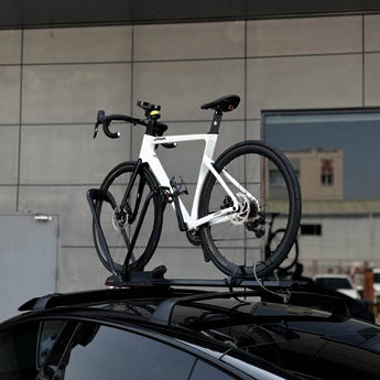 Car roof roof rack holding a bicycle on top of a black vehicle