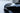 Rear spoiler on glossy black Tesla Model 3, curved lip with side fins