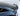 Rear spoiler on gray car rear, glossy black curved trim near trunk edge