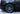 Front wheel close-up with aero wheel cover and tire, dark satin black spokes