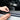 Hands installing a black rubber window seal strip on a car door edge.