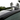 Black roof rack crossbar on car roof with streamlined end cap.