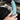 Teal suede steering wheel cover held in place by hands on a black steering wheel.