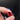 Red aluminum valve stem cap with threaded opening, close-up in hand