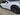 Dark matte aero wheel cover on front wheel of white car, one-piece replacement