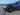 Dark gray aero wheel cover on front wheel of blue car, one-piece replacement