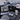 Car tray table, black carbon-fiber texture, holding a laptop and drinkware on console